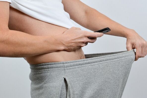 مردی به پایین شلوارش به آلت تناسلی بزرگ شده نگاه می کند